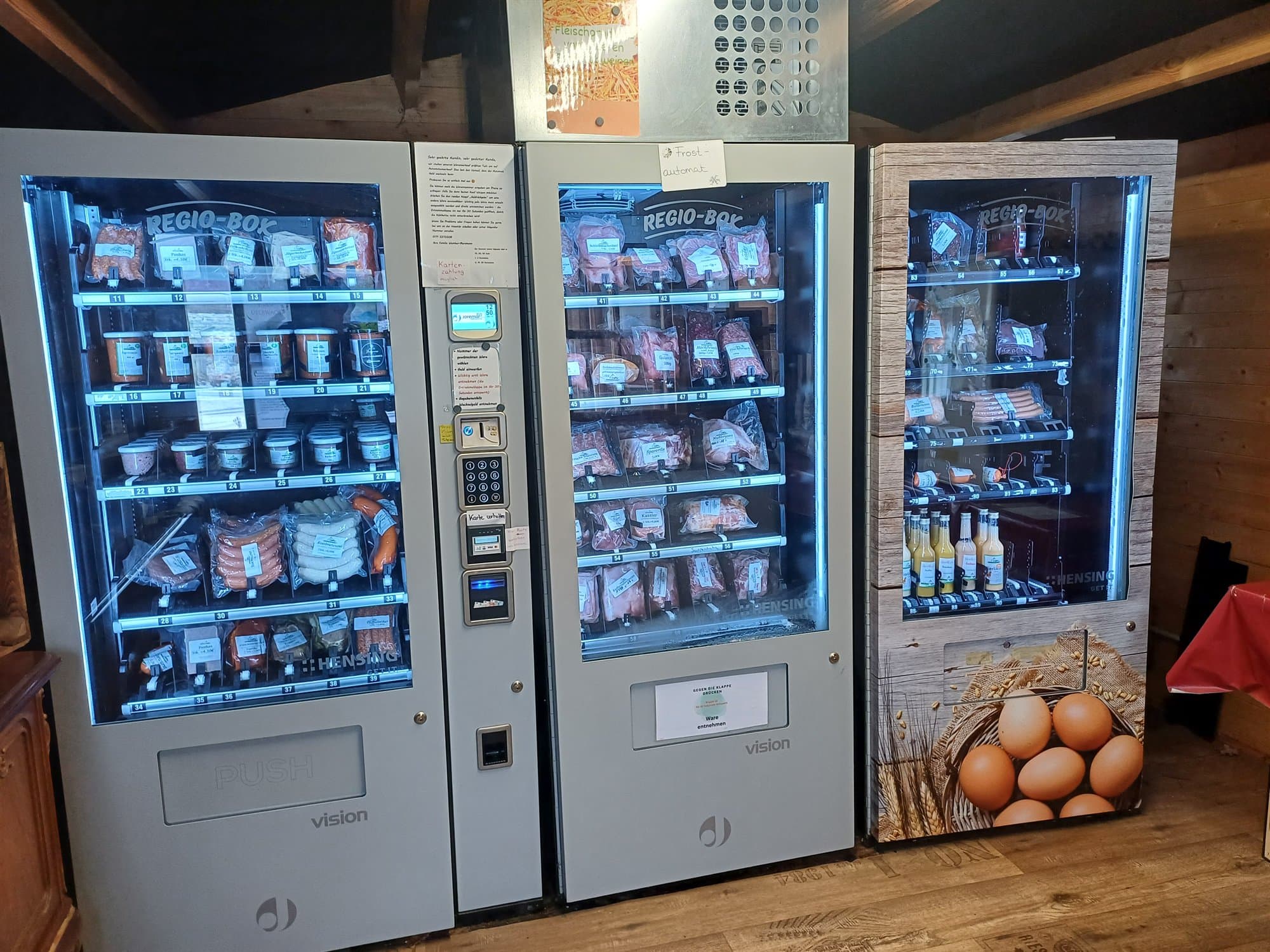 Drei Verkaufsautomaten im Verkaufshaus, gefüllt mit Fleisch, Wurst und Eiern