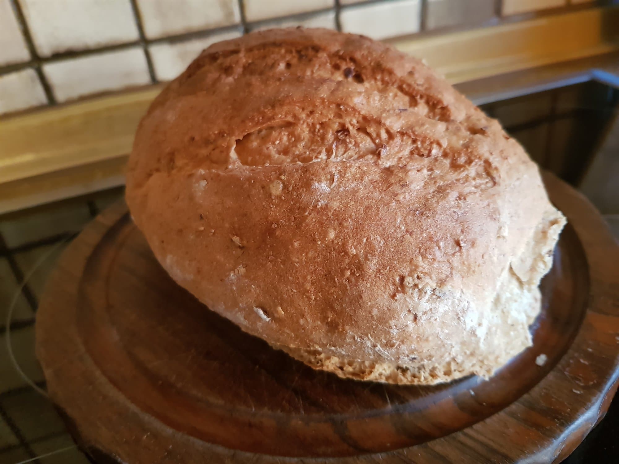 Frisch gebackenes rundes Dinkel-Landbrot auf einem Holzbrett